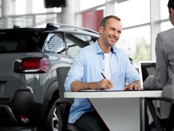 Ein Mann unterzeichnet den Kaufvertrag beim Autoankauf Russee